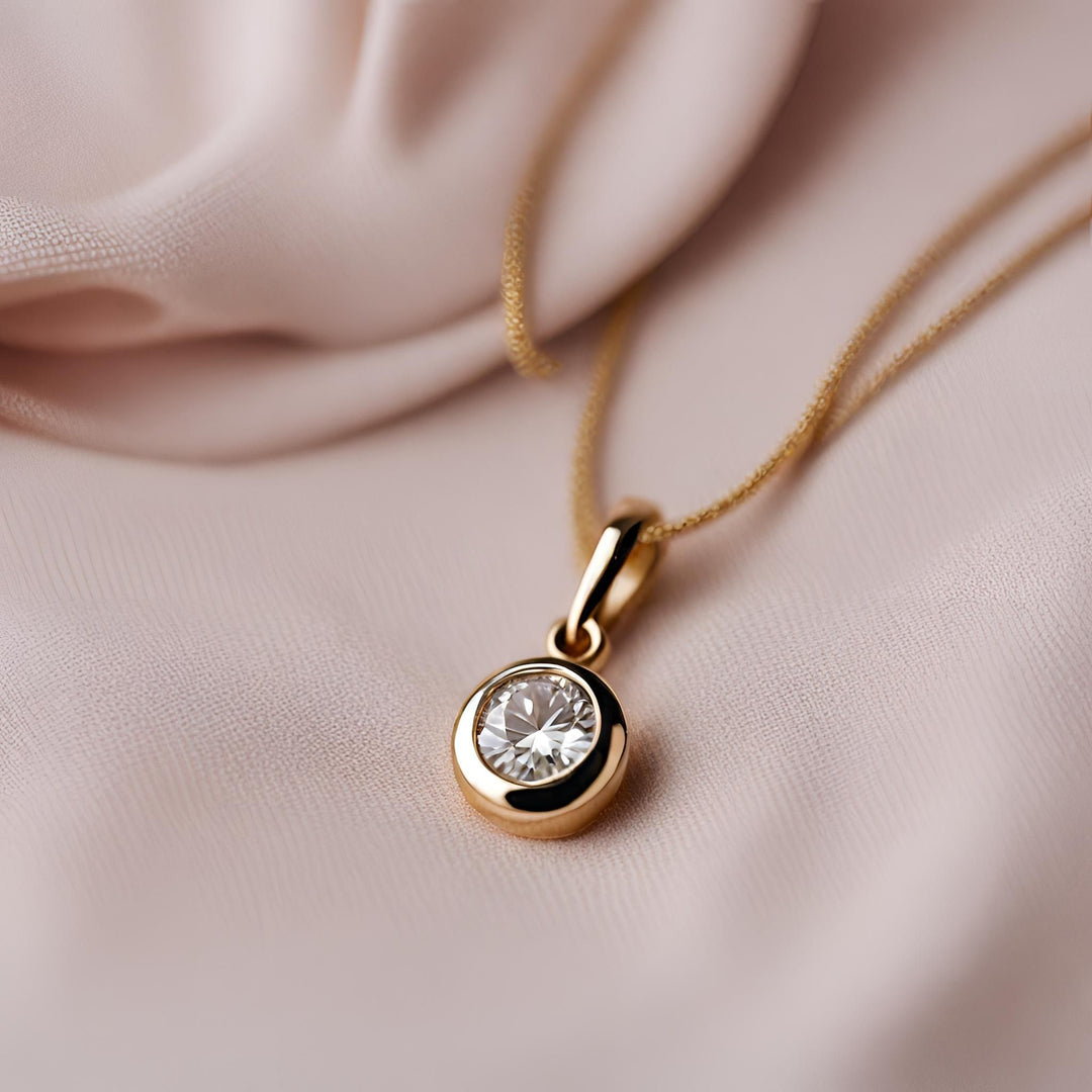 A small round diamond pendant in  14K Gold.  This tiny bezel set diamond necklace has a clean, simple design, making it perfect  for daily wear and layering from Rare Earth Jewelry.