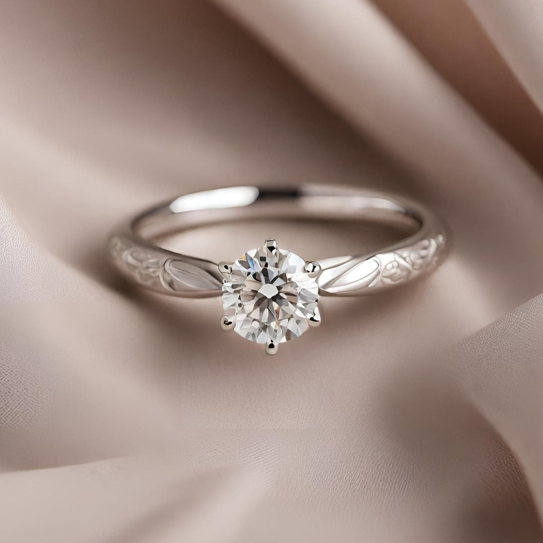 A round diamond solitaire engagement ring with a vintage style engraved band in white gold from Rare Earth Jewelry.