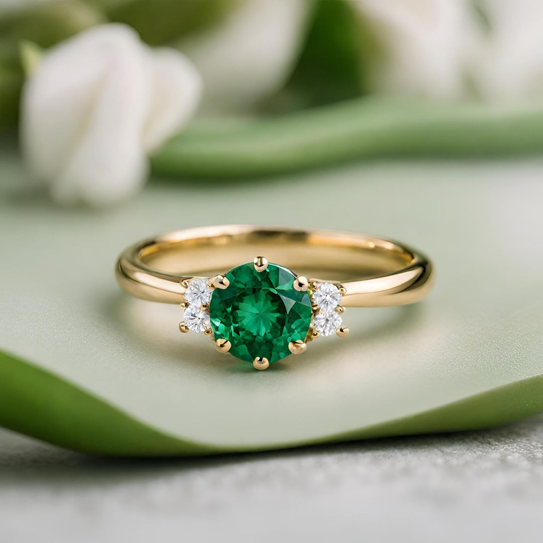 A round emerald engagement ring in a six prong solitaire design with diamond accents in 18K Gold from Rare Earth Jewelry.