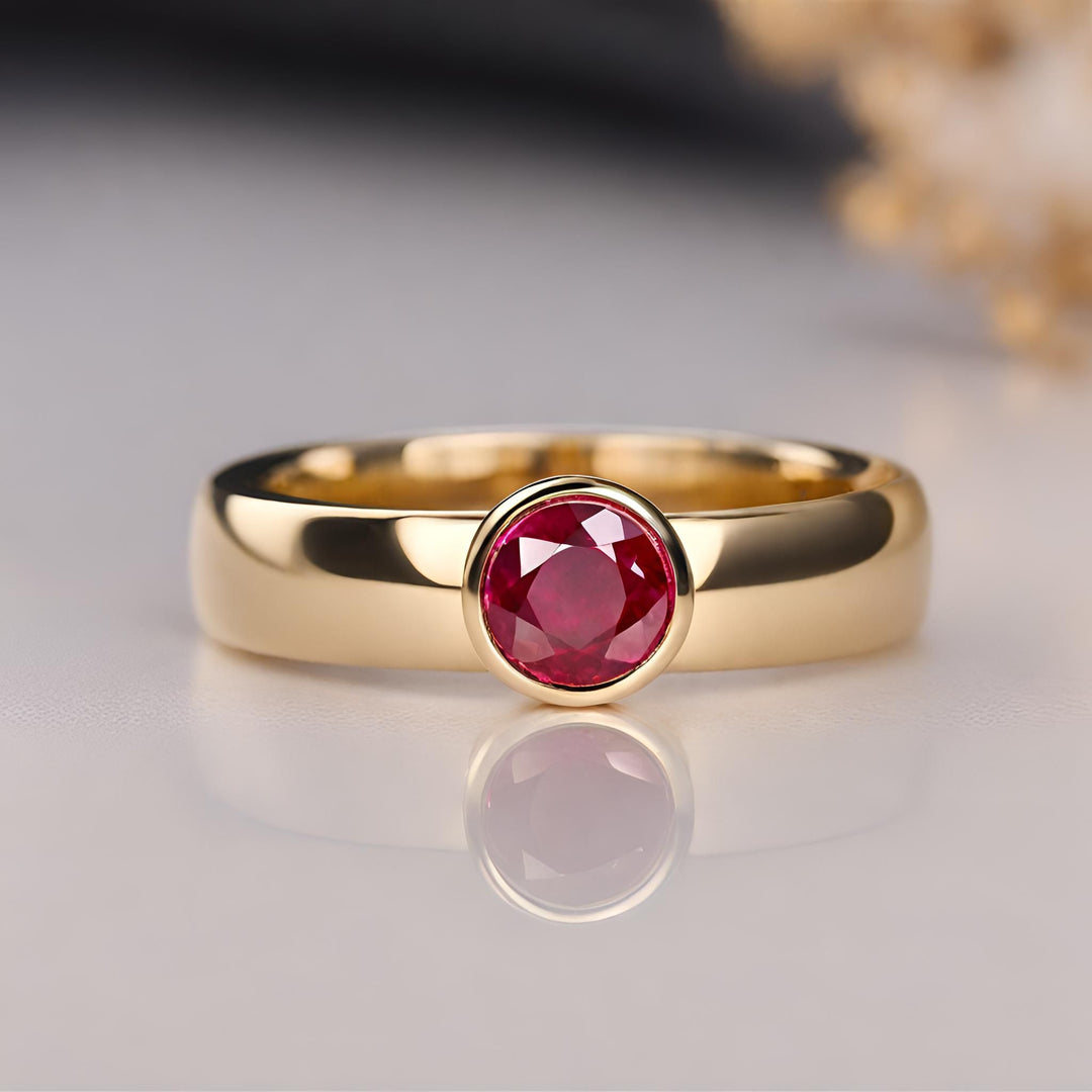 A round bezel set ruby ring on a wide band in 14K Yellow Gold. July birthstone ring for men or women from Rare Earth Jewelry.