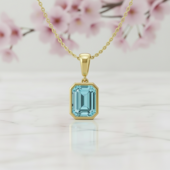Close up of sky blue topaz necklace emerald cut pendant in 14k yellow gold bezel soft aquamarine color | Rare Earth Jewelry