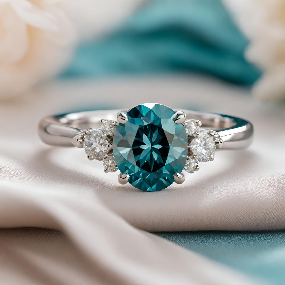 An oval cut teal blue diamond engagement ring with accents in white gold from Rare Earth Jewelry.