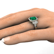 Three stone emerald and diamond ring on the hand side view.