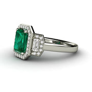 Three stone emerald engagement ring with diamonds in white gold.