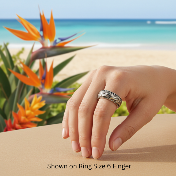 Tropical flower band with hibiscus and ginger engraving in antique white gold shown on finger by Hawaiian beach | Rare Earth Jewelry