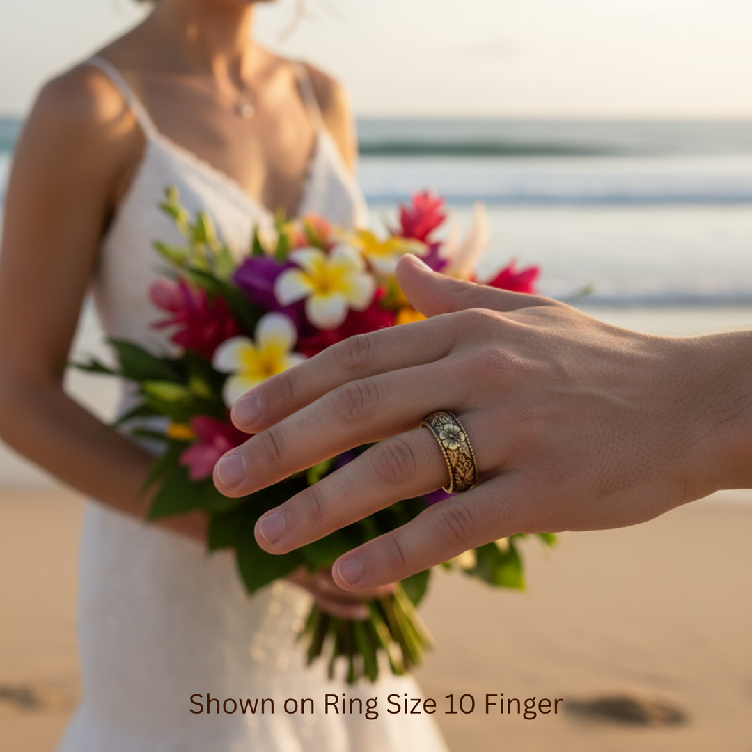 Hawaiian wedding ring with tropical flower and leaf engraving shown on man's hand at beach wedding ceremony | Rare Earth Jewelry