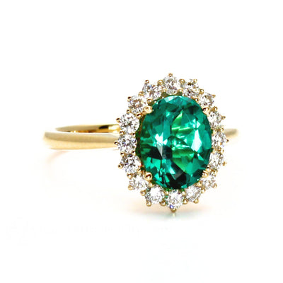 Vintage style oval emerald engagement ring with a diamond halo cluster design in yellow gold