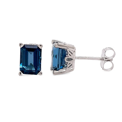 A pair of 14K Gold London Blue Topaz Earrings, Natural Topaz Studs, Emerald Cut December Birthstone Earrings from Rare Earth Jewelry.