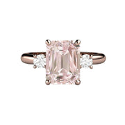 A 2ct emerald cut Pink Morganite engagement ring in a 3 stone style with diamonds in gold or platinum, shown in rose gold from Rare Earth Jewelry.