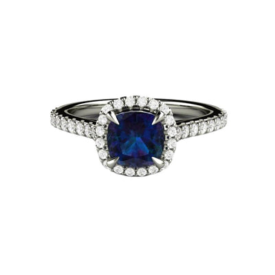 A dainty pave diamond halo engagement ring with a cushion cut Alexandrite, a unique color-changing gemstone that changes from purplish blue to pinkish purple with flashes of teal depending on the light source.