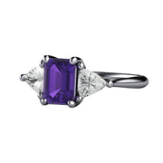 A three stone style Amethyst ring with an Emerald Cut Natural Amethyst and Natural White Sapphire Trillions in White Gold.