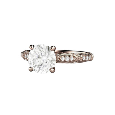 A Round Moissanite solitaire ring with a 1.5ct round Charles & Colvard Forever One Moissanite in a vintage inspired Art Deco design accented with ribbons, milgrain beaded details and diamond accents.
