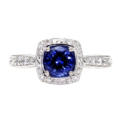 An Art Deco style Blue Sapphire engagement ring with a diamond halo and an engraved scroll design accented with diamonds in 14K, 18K Gold or Platinum..