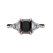 A black diamond engagement ring in a 3 stone style with an emerald cut natural black diamond and white sapphire trillions, shown here in rose gold.