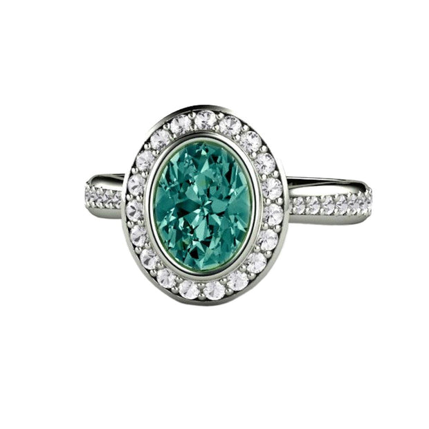 An oval blue green sapphire engagement ring with a bezel set diamond halo in gold or platinum from Rare Earth Jewelry.