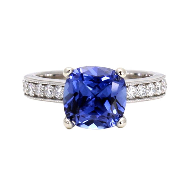 A large 3ct square cushion cut Blue Sapphire engagement ring in a cathedral solitaire setting with diamond accents and a milgrain beaded edge in gold or platinum from Rare Earth Jewelry.