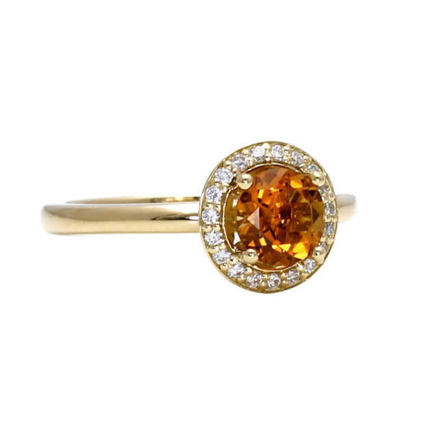 A round natural Citrine ring with a diamond halo in yellow gold.  The stone is orange and yellow and is the birthstone for November.