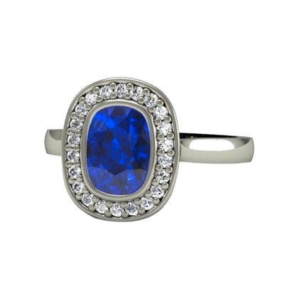 A bezel set blue sapphire engagement ring with a large rectangular cushion cut lab grown blue sapphire and diamond halo, a modern design in gold or platinum.