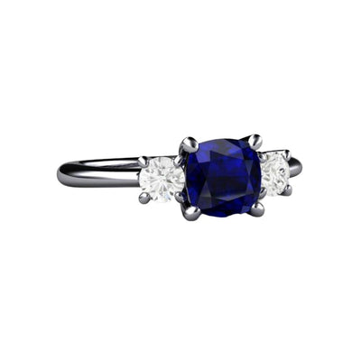 A 3 stone style blue sapphire ring with a square cushion cut lab grown blue sapphire and moissanite accents in gold or platinum