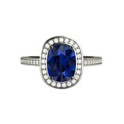 A sleek and contemporary Blue Sapphire engagement ring with a rectangular cushion cut lab grown Blue Sapphire and a natural diamond halo in gold or platinum.