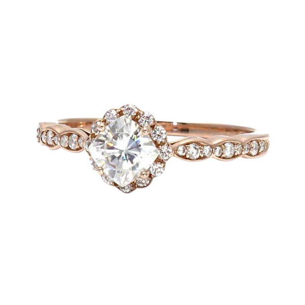 A vintage style Moissanite halo engagement ring with a cushion cut Charles & Colvard Forever One Moissanite center and diamond accents.  The ring has a dainty and feminine scalloped halo and band.