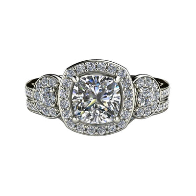 A cushion cut Moissanite engagement ring with a Charles & Colvard Forever One Moissanite center and diamond halo and 3 stone design with matching wedding band in gold or platinum.