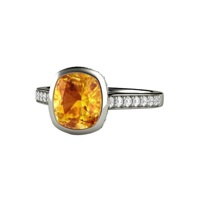 A yellow Sapphire engagement ring in a cushion cut solitaire design with diamond accents in gold and platinum.
