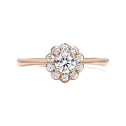 A romantic and feminine styled diamond engagement ring with a flower shaped diamond halo or cluster surrounding a .30ct natural diamond center, shown in rose gold.