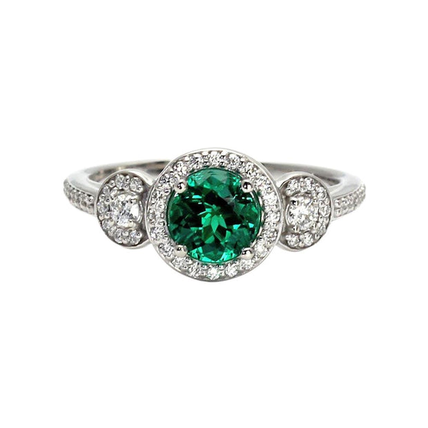 Three-stone emerald and diamond engagement ring with sparkling halos and accent diamonds on the band. May birthstone jewelry from Rare Earth Jewelry.