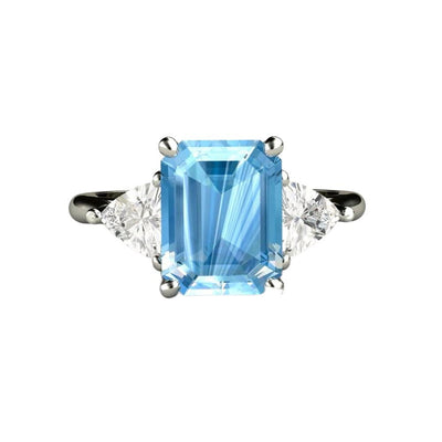 A large emerald cut natural Aquamarine ring in a three stone style with white sapphire trillions.  March Birthstone blue stone engagement ring from Rare Earth Jewelry.