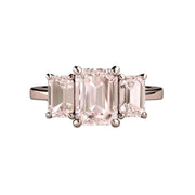 A natural Morganite engagement ring in a three stone style with emerald cut peach pink Morganite in gold or platinum, shown in rose gold, available only at Rare Earth Jewelry.