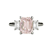 A natural Morganite engagement ring in a 3 stone style with emerald cut Morganite and natural White Sapphire side stones in gold or platinum from Rare Earth Jewelry.