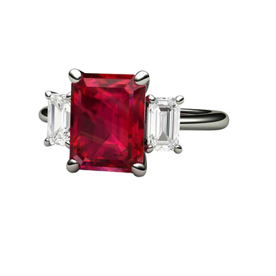 A large 3 carat emerald cut Ruby ring in a 3 stone style with White Sapphire accents, one on each side of the lab grown Ruby center available in gold or platinum, and shown here in white gold, exclusively from Rare Earth Jewelry.