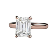 A 3 carat emerald cut White Sapphire solitaire engagement ring in rose gold, a classic style with a white sapphire instead of a diamond.
