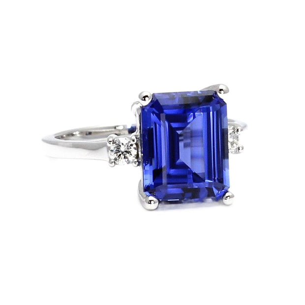 A large emerald cut lab grown Blue Sapphire ring in a 3 stone style with round diamonds, one on each side.  An affordable blue sapphire engagement ring in gold or platinum from Rare Earth Jewelry.