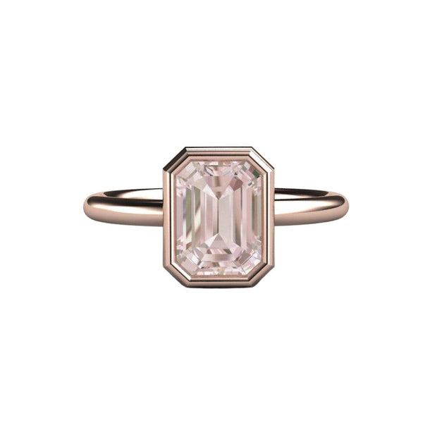 An emerald cut natural morganite ring in a bezel set solitaire engagement ring, shown in rose gold from Rare Earth Jewelry..