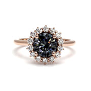 A round gray moissanite enagement ring with a vintage style cluster halo design in gold or platinum, shown in rose gold from Rare Earth Jewelry.