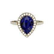 A large pear cut Blue Sapphire engagement ring with pave set diamond halo and shank. A 2.75ct lab grown pear shaped Blue Sapphire ring shown in yellow gold from Rare Earth Jewelry.