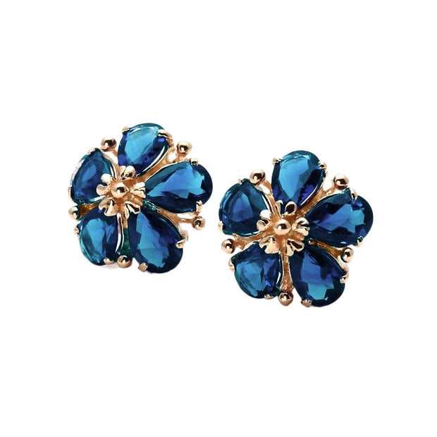 A pair of 14K Gold flower shaped London Blue Topaz earrings, with pear cut natural London Blue Topaz petals and solid gold floral design. Unique December birthstone earrings from Rare Earth Jewelry.