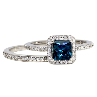 A princess cut natural London Blue Topaz engagement ring with a square diamond halo design and matching diamond wedding band.  This December birthstone bridal set is available in gold or platinum from Rare Earth Jewelry.
