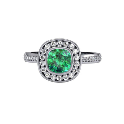 An emerald engagement ring with a modern, sophisticated bezel setting with a cushion cut lab created emerald and a diamond halo in gold or platinum from Rare Earth Jewelry.