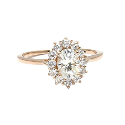 A dainty and feminine vintage style oval Moissanite engagement ring with a halo cluster design in gold or platinum from Rare Earth Jewelry.