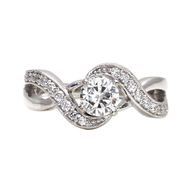 A solitaire engagement ring with a Charles & Colvard Forever One Moissanite and a modern infinity design with pave set diamonds, an eco friendly ethical diamond alternative engagement ring from Rare Earth Jewelry.