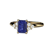 A natural Tanzanite ring with diamond accents, three diamonds on each side of an emerald cut natural Tanzanite in gold or platinum from Rare Earth Jewelry.