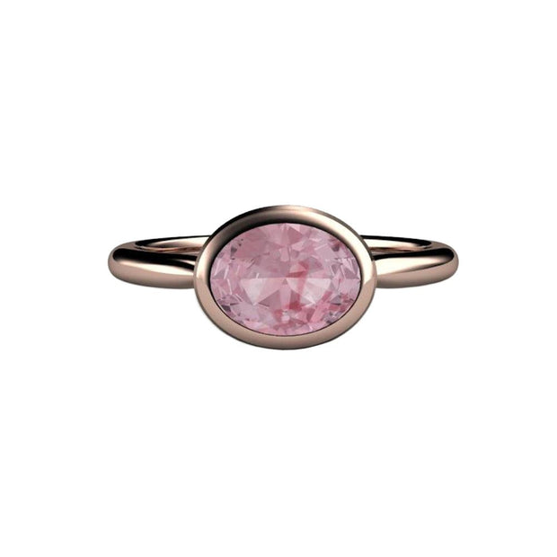 Minimalist Pink Sapphire engagement ring with a bezel set 1.75ct oval-cut light peach pink champagne Sapphire in an east-west setting. Engagement rings for an active lifestyle from Rare Earth Jewelry