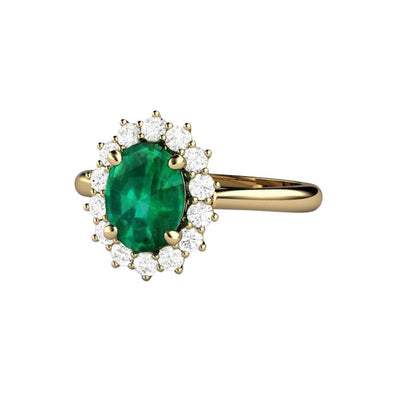 Feminine Emerald engagement ring with a 1.15ct oval cut green Emerald and a halo of natural diamonds. Classic vintage-style cluster setting in Gold or Platinum.