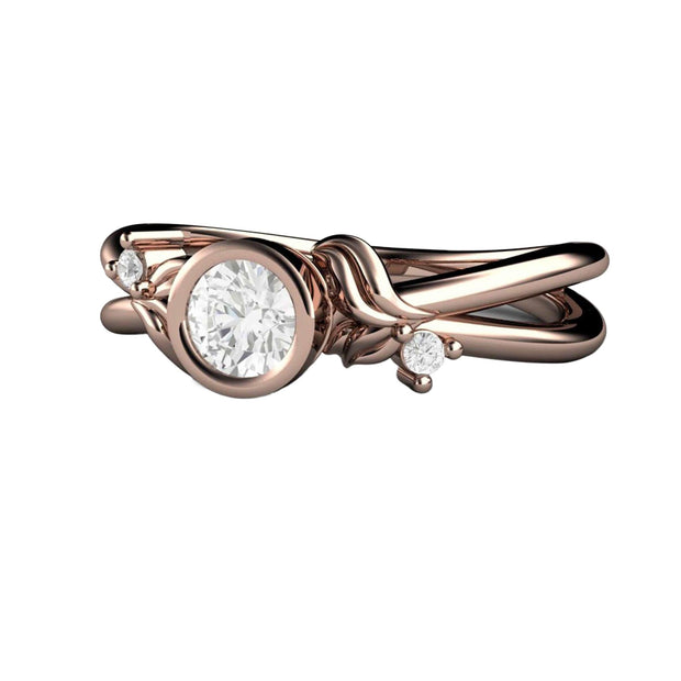 A simple and modern .25ct diamond engagement ring in a round bezel setting with a floral bud and leaf design.  It's a minimalist style and is shown in rose gold.ign 