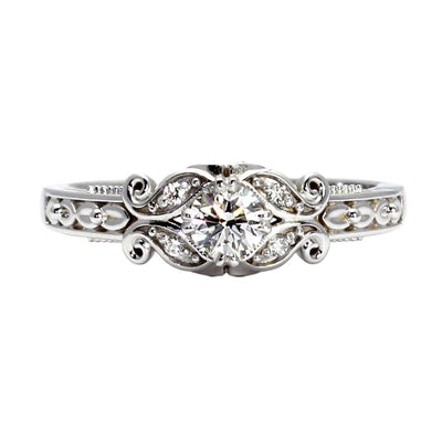 A vintage style diamond engagement ring with an Art Deco solitaire design with a round natural diamond, filigree in gold or platinum.