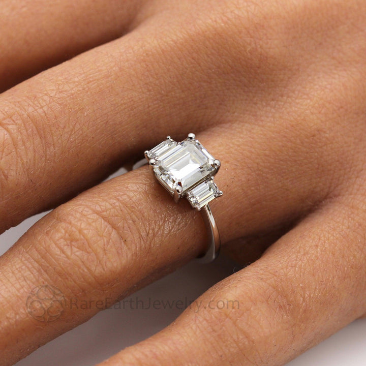 Three Stone Emerald Cut Moissanite Engagement Ring Close Up of Ring on Finger | Rare Earth Jewelry