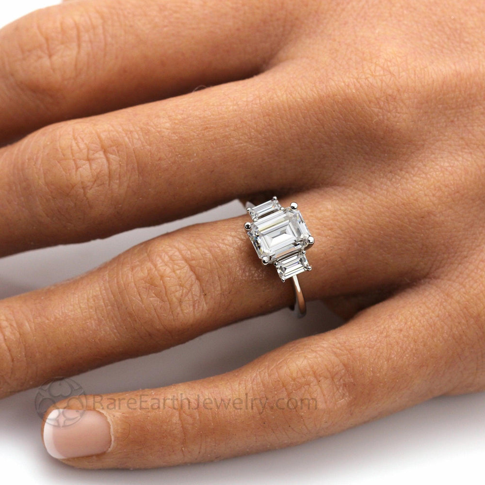 Three Stone Emerald Cut Moissanite Engagement Ring on Hand, Lab Created Diamond Alternative Engagement Rings | Rare Earth Jewelry